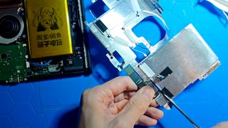 A still from a YouTube video showing a disassembled Nintendo Switch 2 being cut apart with a pair of scissors