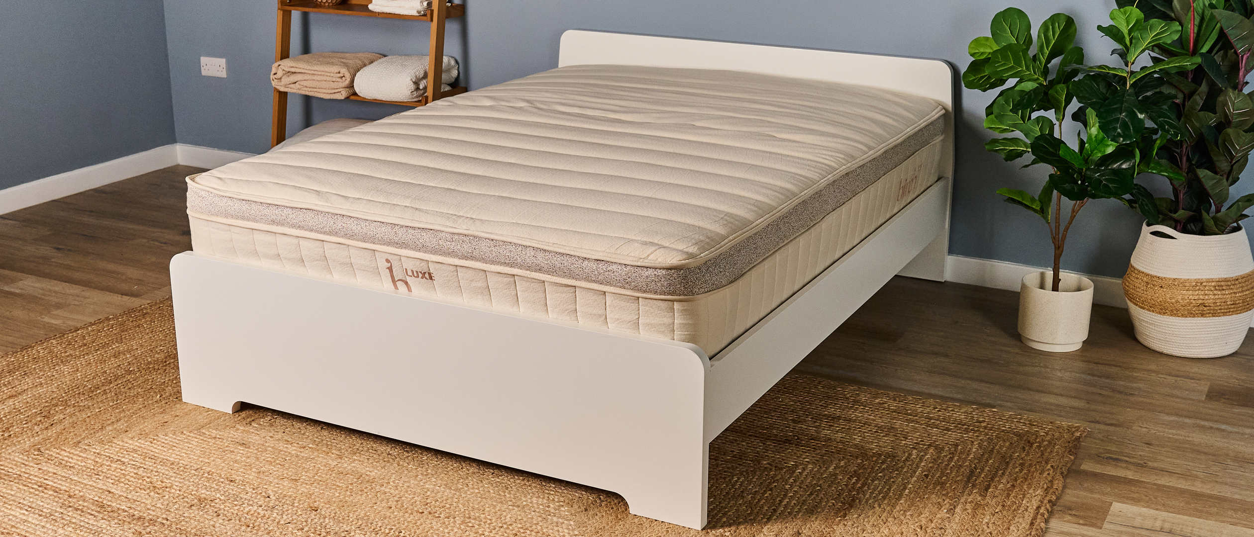 The Birch Luxe Natural mattress on a white bed frame in a open bedroom