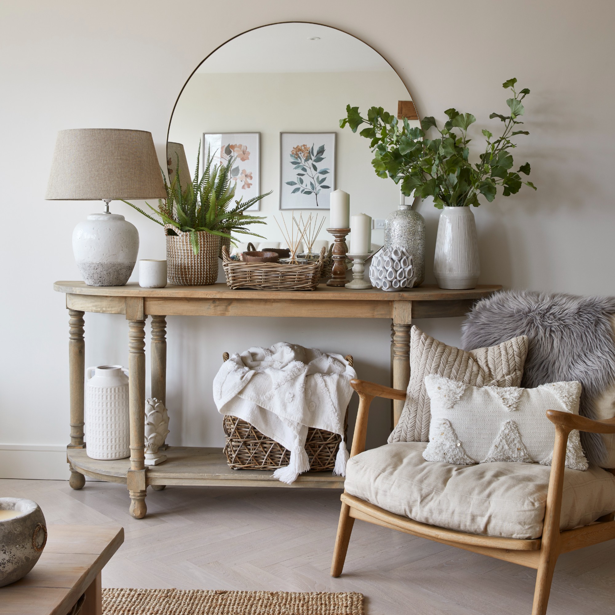 A neutral living room with a rustic wooden console table decorated with an arched mirror on top