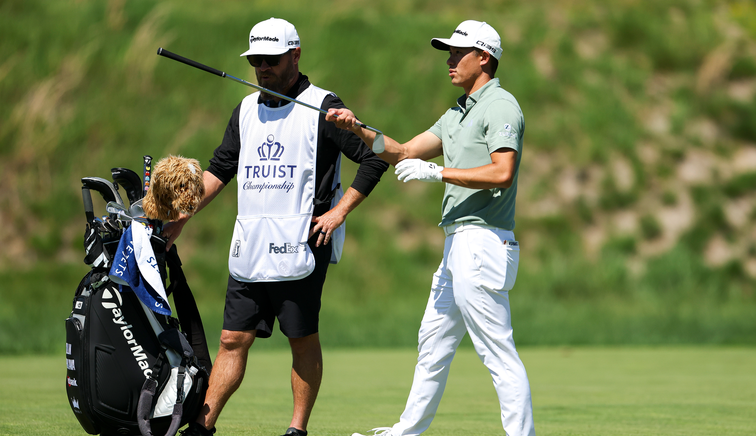 Collin Morikawa hands a club to his caddie at the Truist Championship