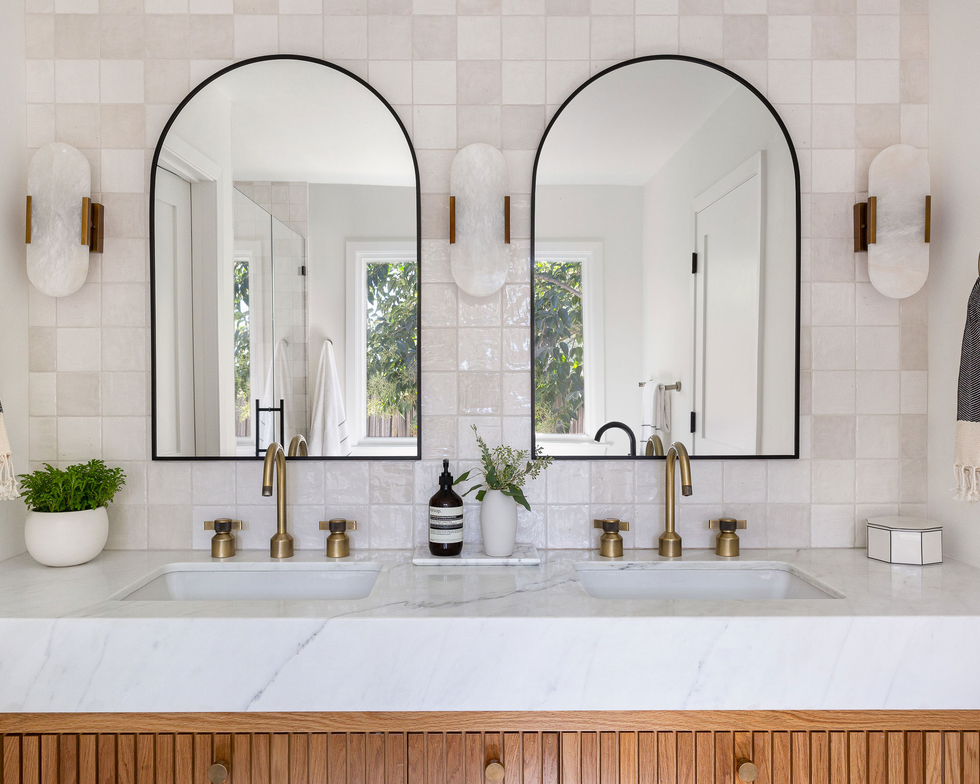 Double vanity in marble with square tile texture wall and two arch mirrors.jpg