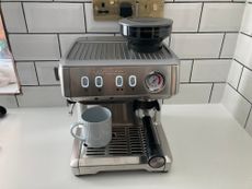Ariete 1313 Espresso Machine with lights on and mug in place in a white kitchen with metro tiles