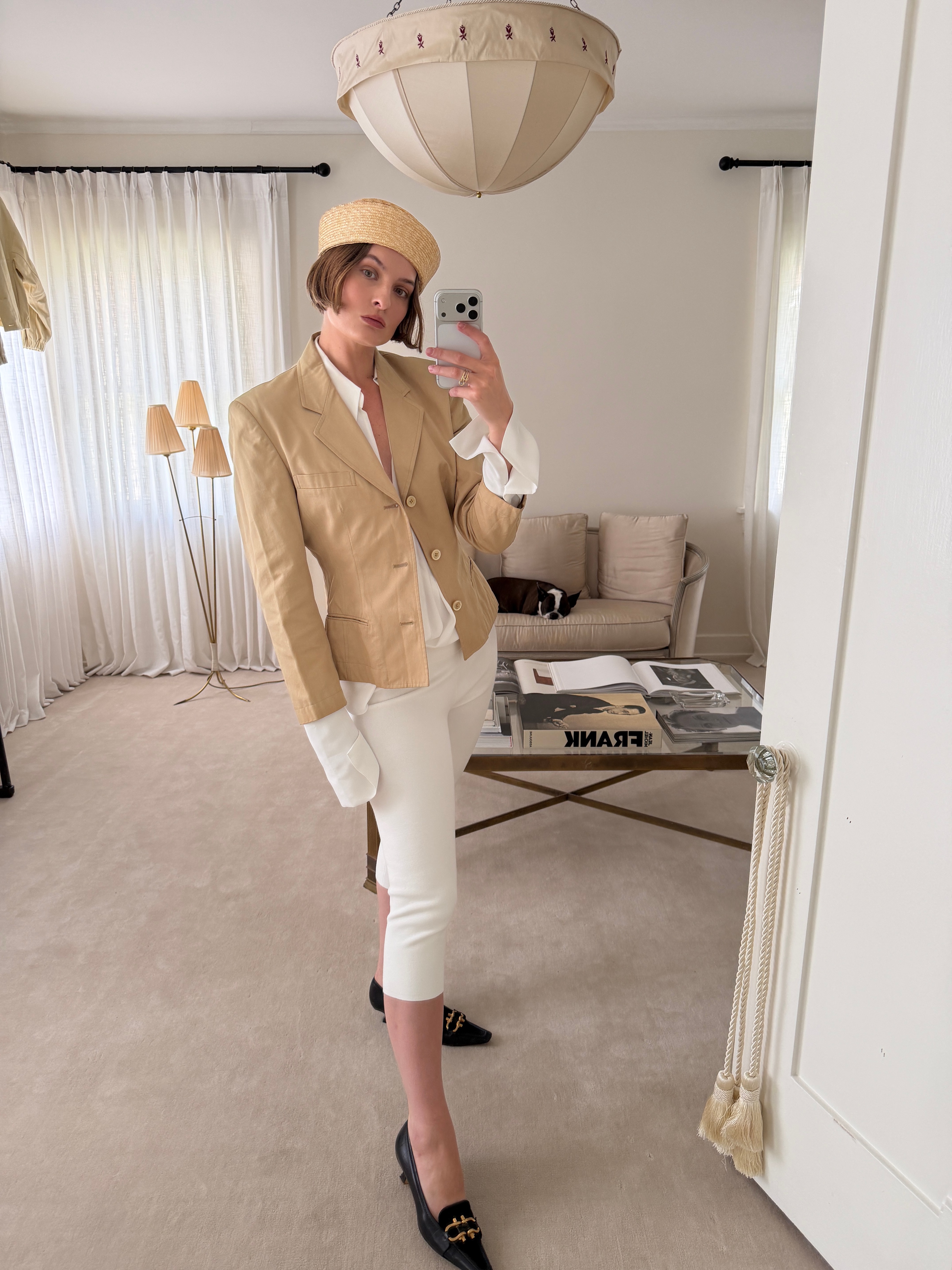 Christie Tyler takes a mirror selfie in a butter yellow-adjacent blazer and toque, styled with white capris and black kitten heels