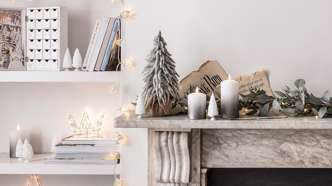 mantelpiece decorated for christmas with candles, mini christmas tree and garland next to shelf