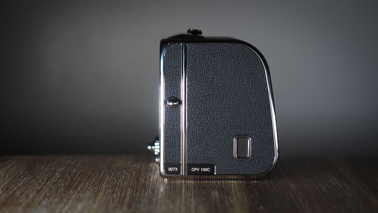 The Hasselblad 907X &amp; CFV 100C medium format camera with digital back, on a wooden table with artistic lighting