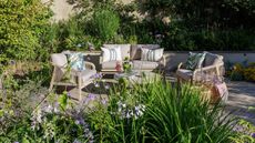pale grey outdoor sofa and armchairs on a patio surrounded by planting
