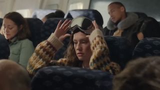 En kvinna som använder ett Apple Vision Pro-headset på ett flygplan.