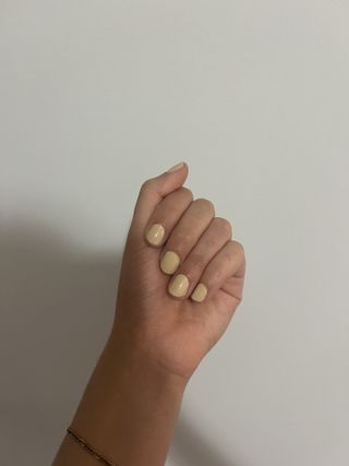 Gabrielle Ulubay's hand with yellow-beige nail polish on