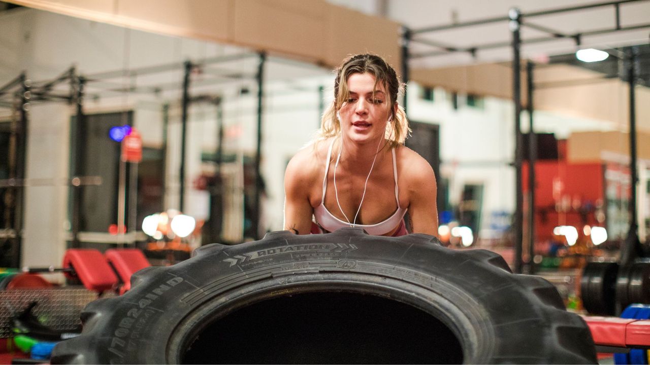 Hybrid training: A woman pushing a tyre at the gym