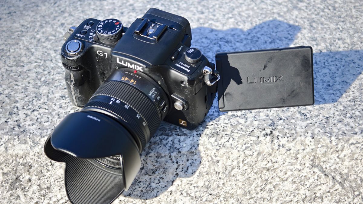 The Panasonic Lumix G1 mirrorless camera and 14-45mm kit lens on a marble surface in daylight