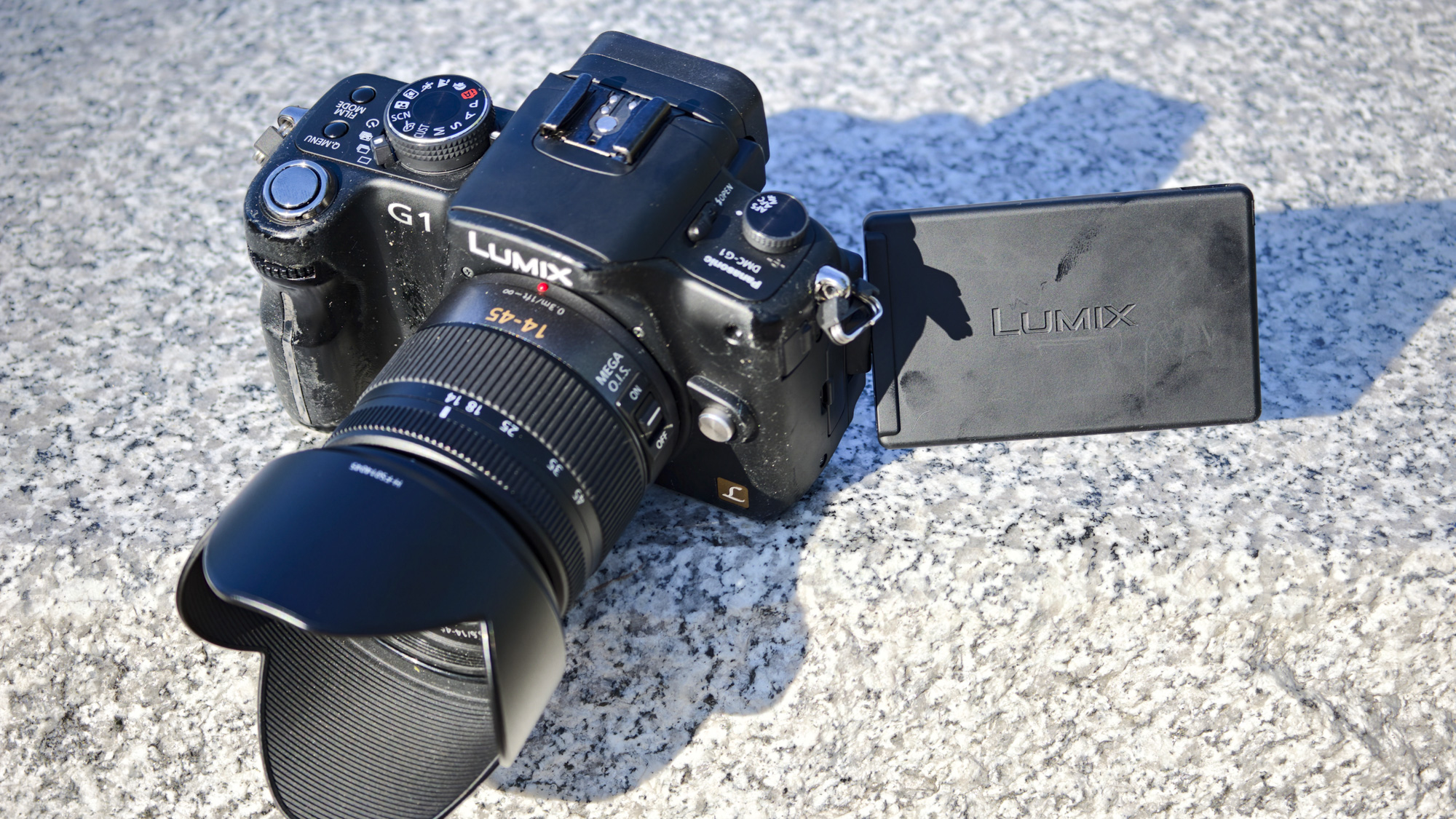 The Panasonic Lumix G1 mirrorless camera and 14-45mm kit lens on a marble surface in daylight