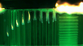 an image of material burning. small flames go down lines at the left. on the right is another sample with a very large flame at top