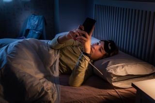 Teenage in girl in bed on her phone late at night