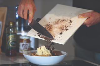 Male cyclist adding chocolate shavings as part of making cookie dough protein balls