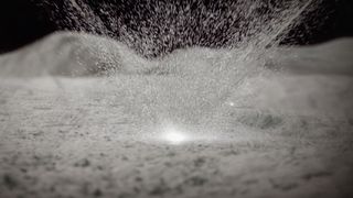 black and white image of an impact launching dust up from a grey surface