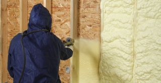 man spraying foam insulation in house