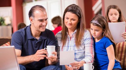 Mom, dad and child look at a piece of paper while other children stay in the background