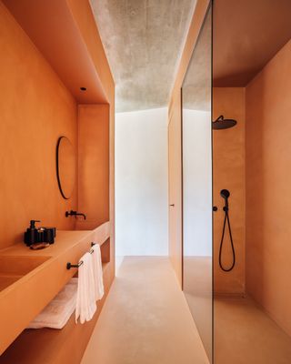 An orange bathroom with clean lines and black bathroom brassware