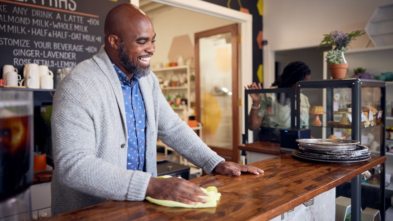 The owner of a tea shop wipes down his front counter.