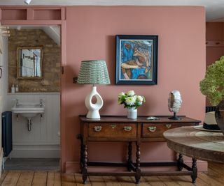 A hallway scheme with a vintage dresser paired with a contemporary table lamp and a vintage framed artwork