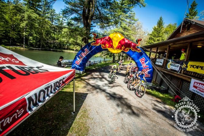 A string of racers pull through the finishing arch of the final stage of the Trans-Sylvania Epic
