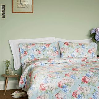 bedroom with floral printed bedding set and photoframe on wall