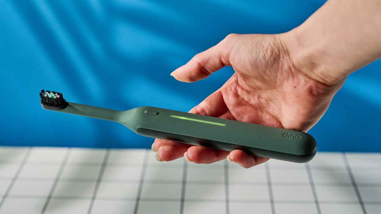 Quip Ultra Next Generation Smart Sonic Electric Toothbrush photographed in front of a blue background.
