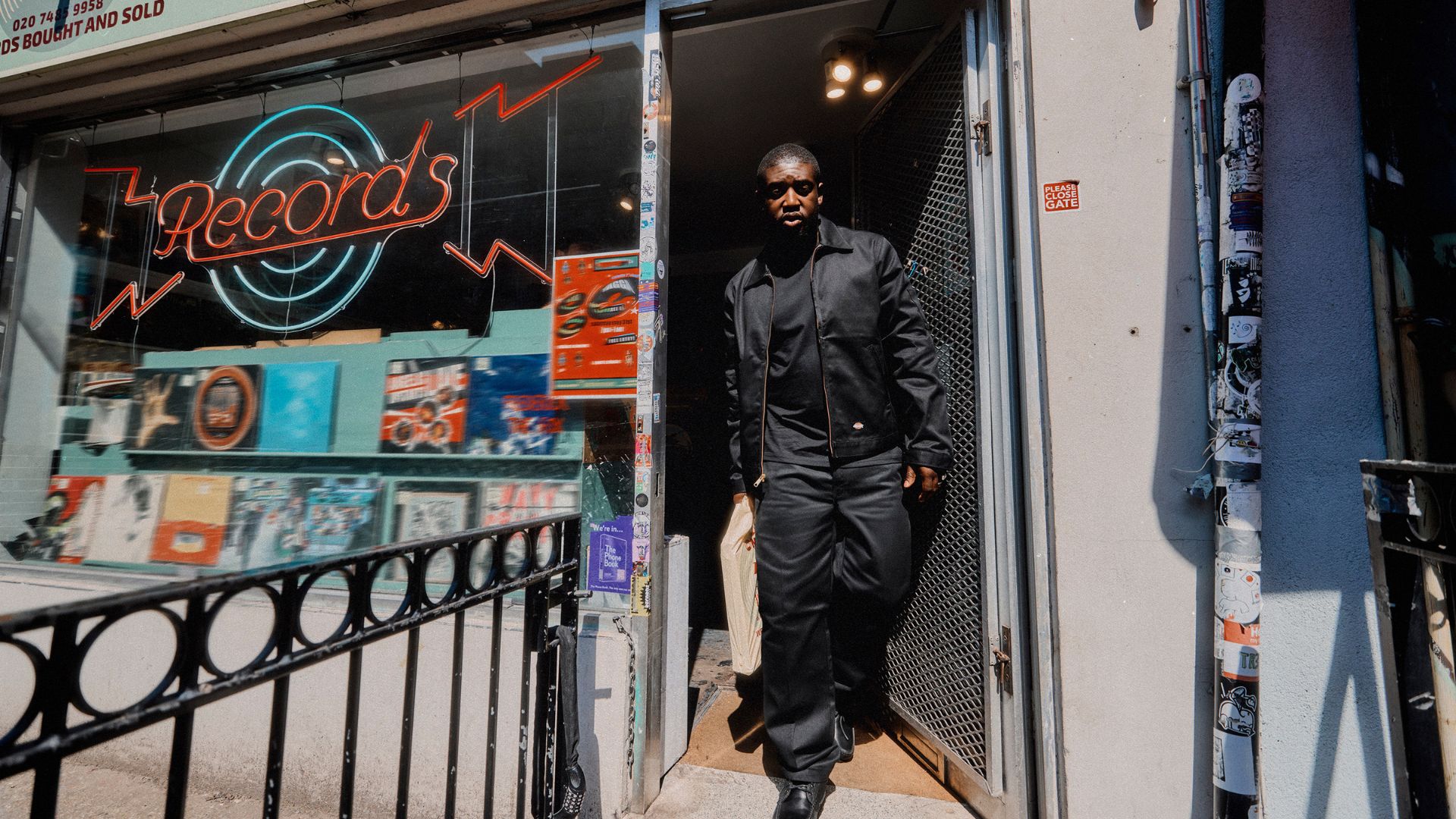 an image of a male model wearing Dickies 247 collection walking out of a classic record store
