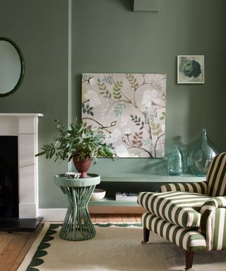 green living room with green stripe armchair botanical print and low shelf storage