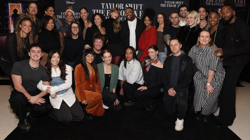 Taylor Swift poses with a large group of people in front of a promotional backdrop for "The End of an Era," a Disney+ docuseries.