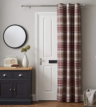 a check thermal curtain covering a white door in a cosy living room