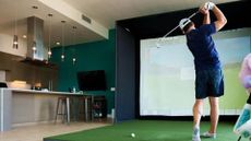 A golfer playing a round of simulation golf in his kitchen