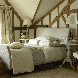 bedroom with wooden frame white wall and white bed with cushions