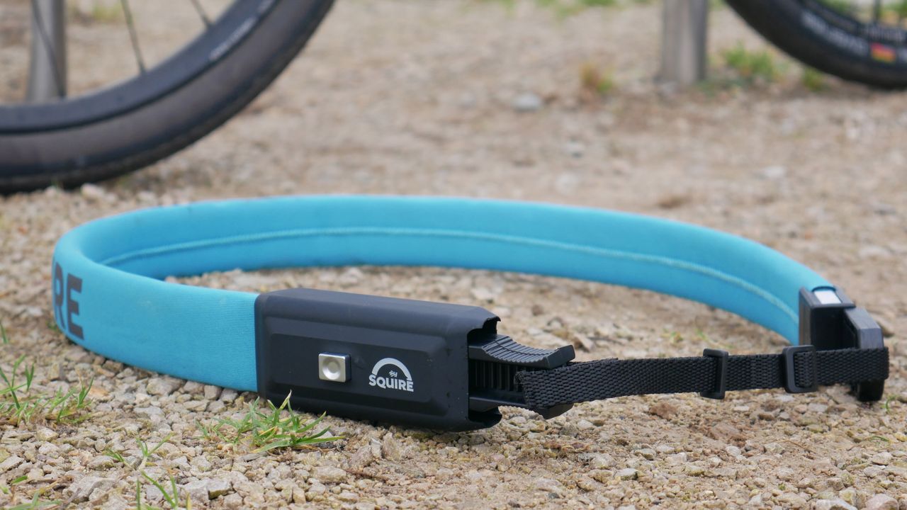 A blue squire straplok laid on a loose gravel surface with its wearable adapter fitted