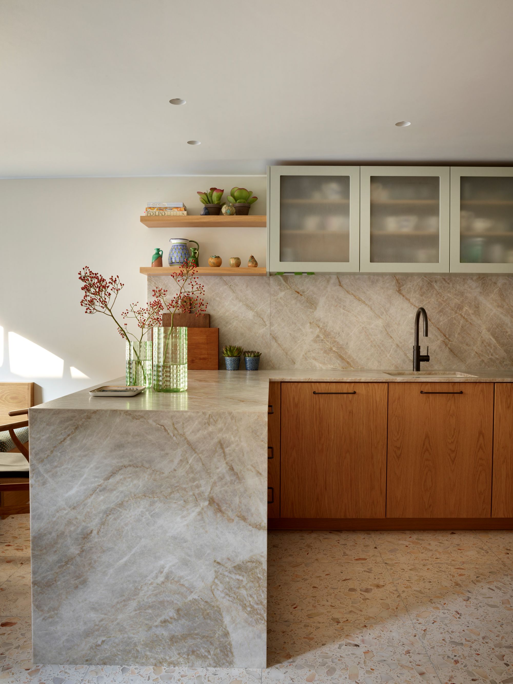 a small kitchen with large terrazzo tiled floors, wooden cabinets, and marble counters