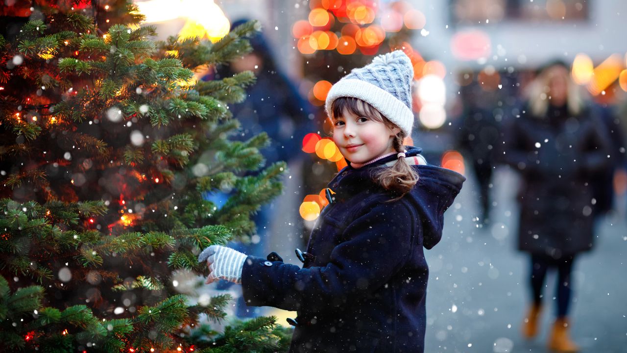 A girl standing next to a Christmas tree