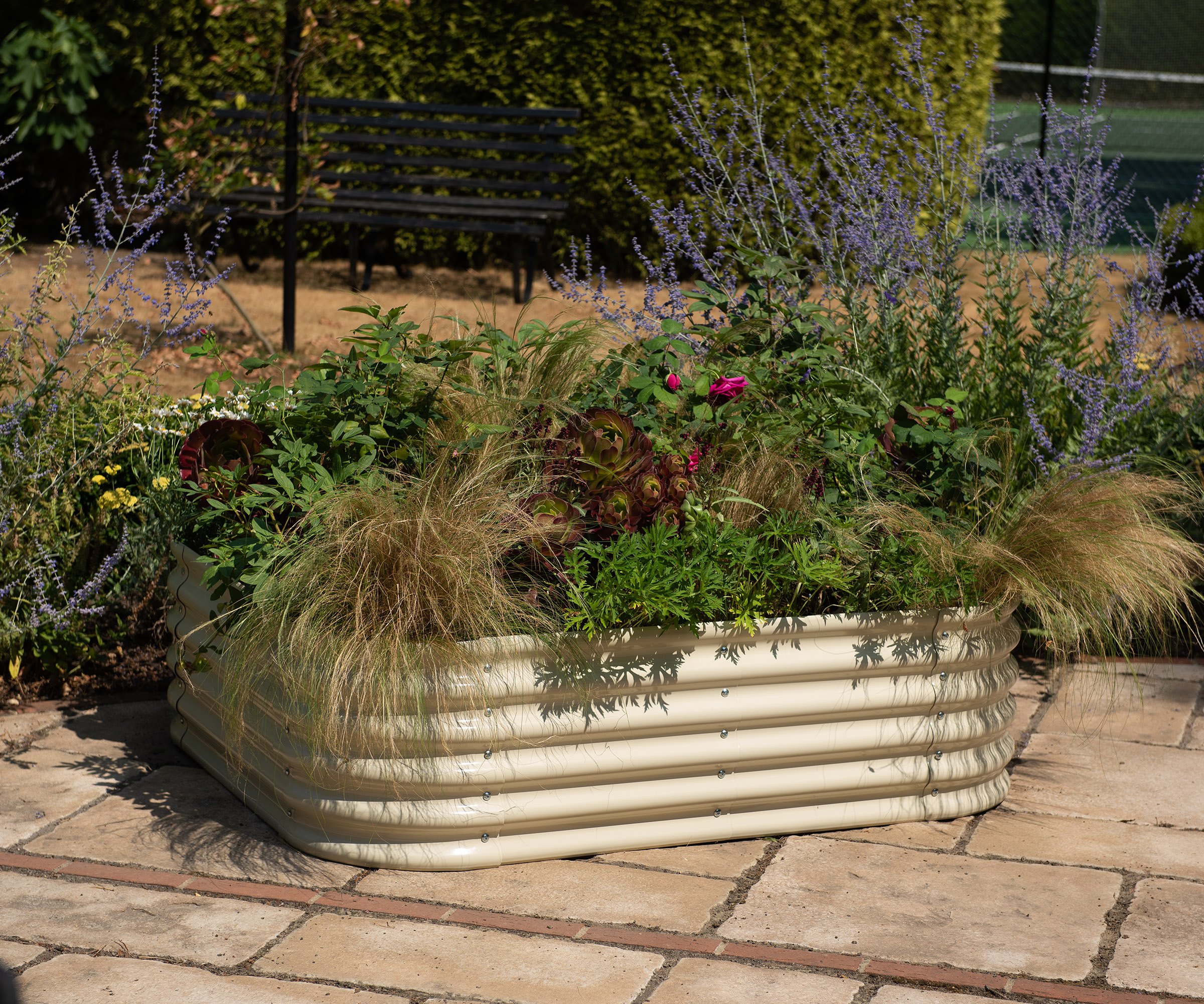 Corrugated metal planter filled with plants like grasses and foliage