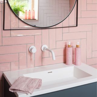 Pink bathroom wall tiles with floating wall mounted tap in white