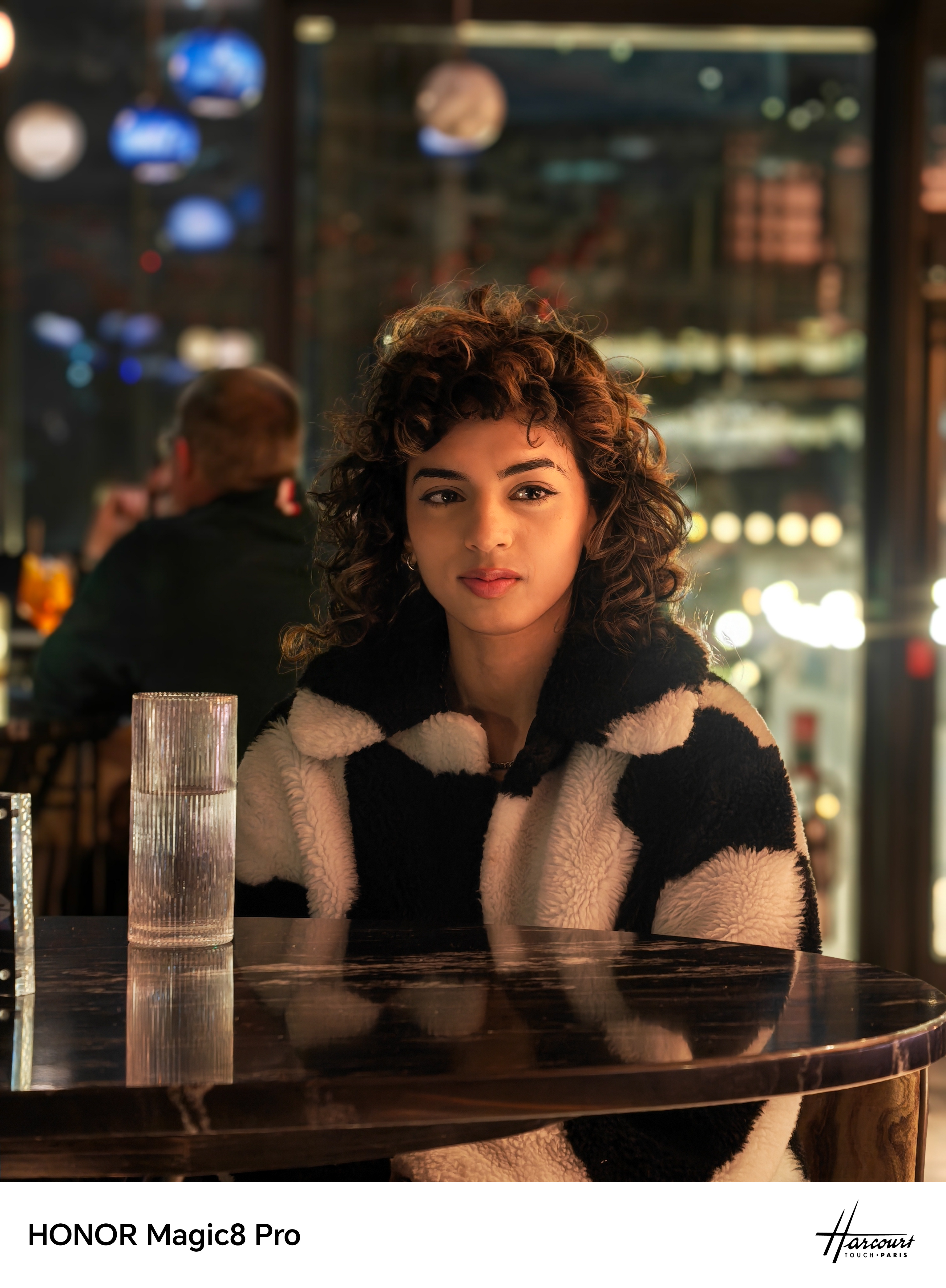 A model sitting in a bar having a drink shot on an Honor Magic 8 Pro