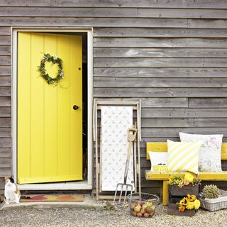 wooden exterior with yellow door and bench