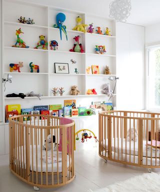 white nursery with built in storage and two wooden cribs