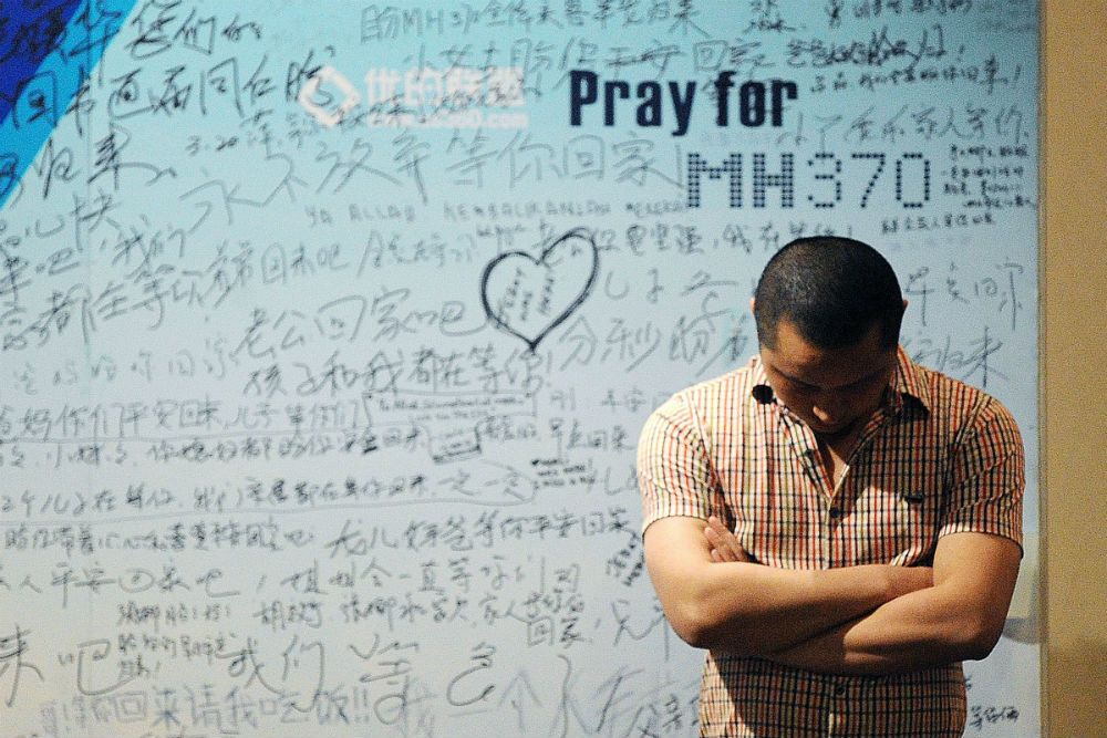 A victim's relative stands in front of tributes to flight MH370