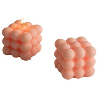 Two peach colored bubble candles on a white background.