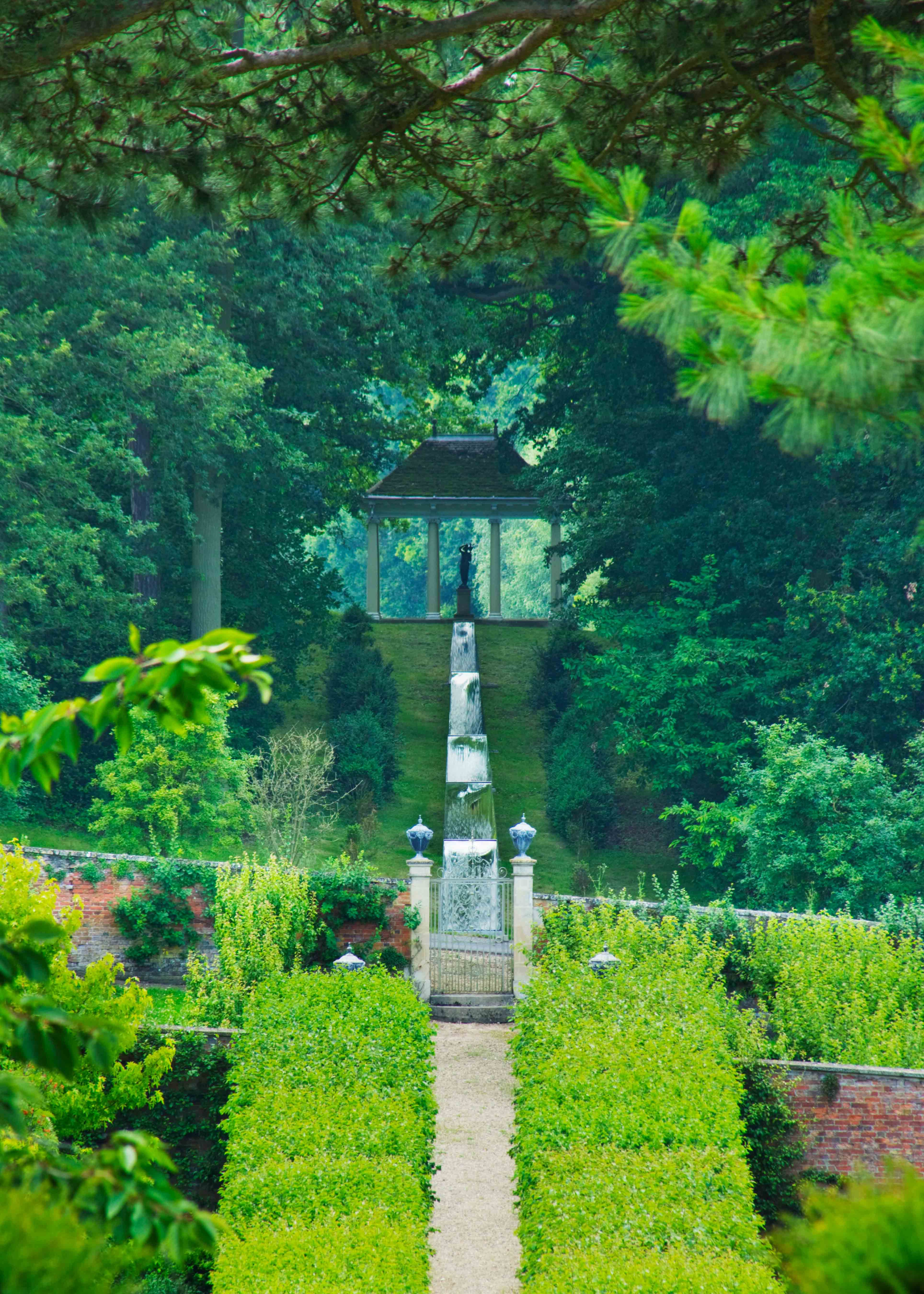 a beautiful garden path surrounded by rich greenery with a water rill running through the centre