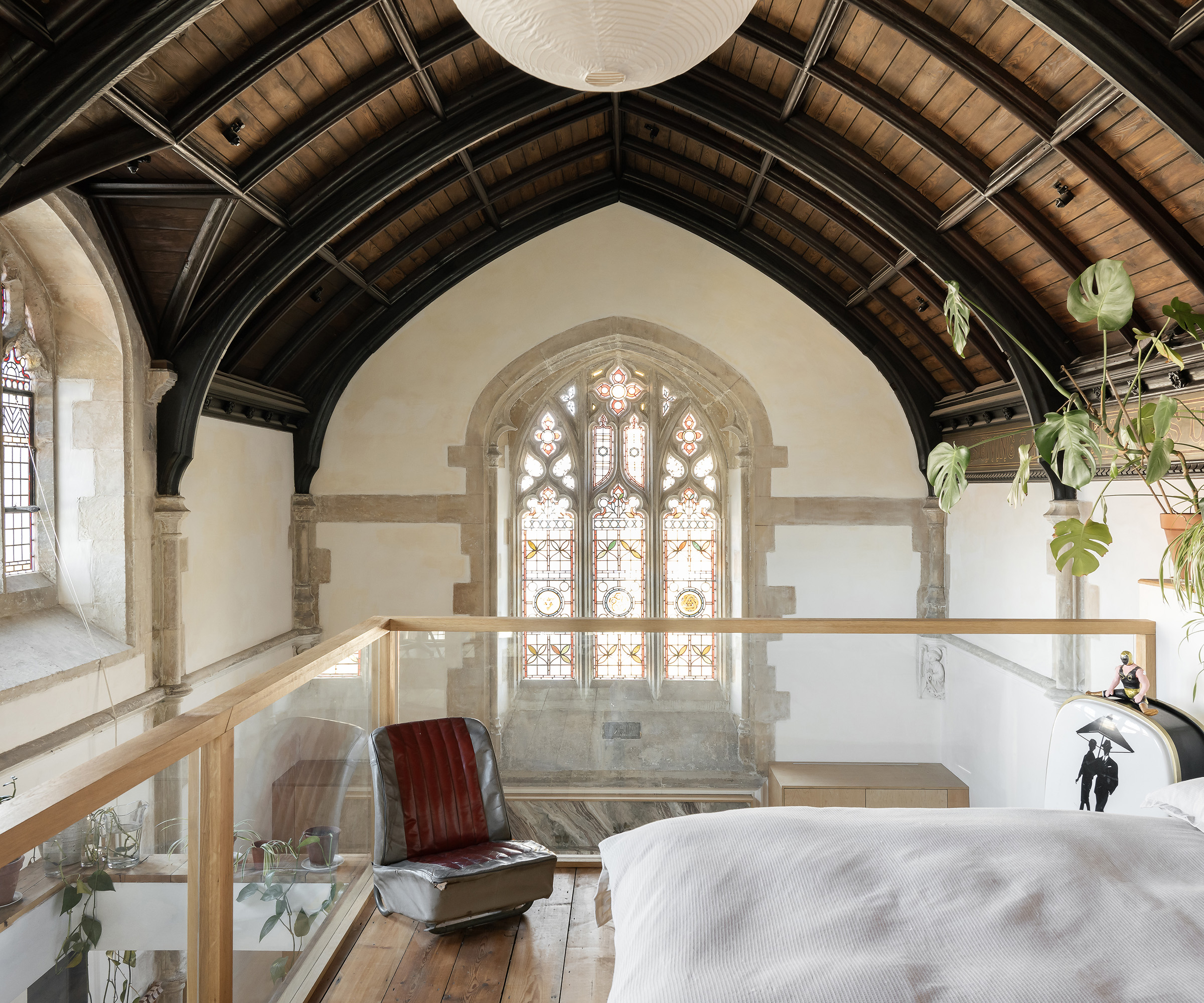 A mezzanine bedroom in a converted chapel looking out to a stained glass window