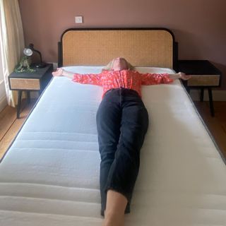 The Origin Hybrid mattress being tested in a bedroom with pink walls and a bed with a rattan headboard