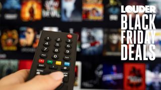 Hand on a TV remote control with a TV screen in the background