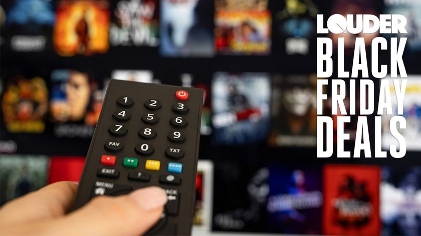 Hand on a TV remote control with a TV screen in the background