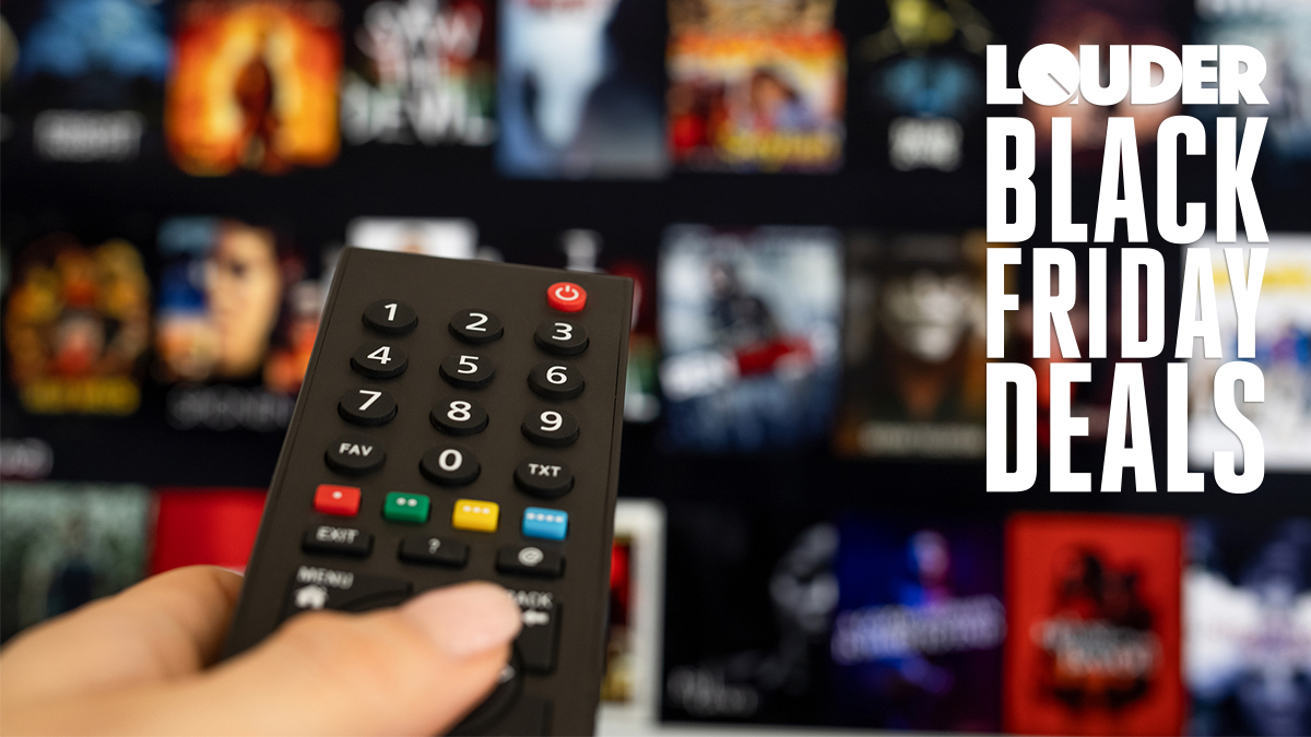 Hand on a TV remote control with a TV screen in the background