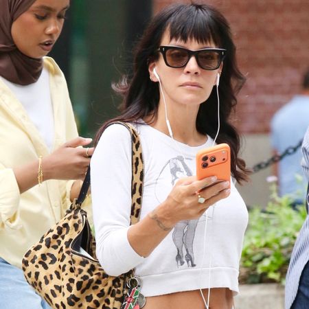 Lily allen wears sunglasses, a cropped white t-shirt and a leopard bag.